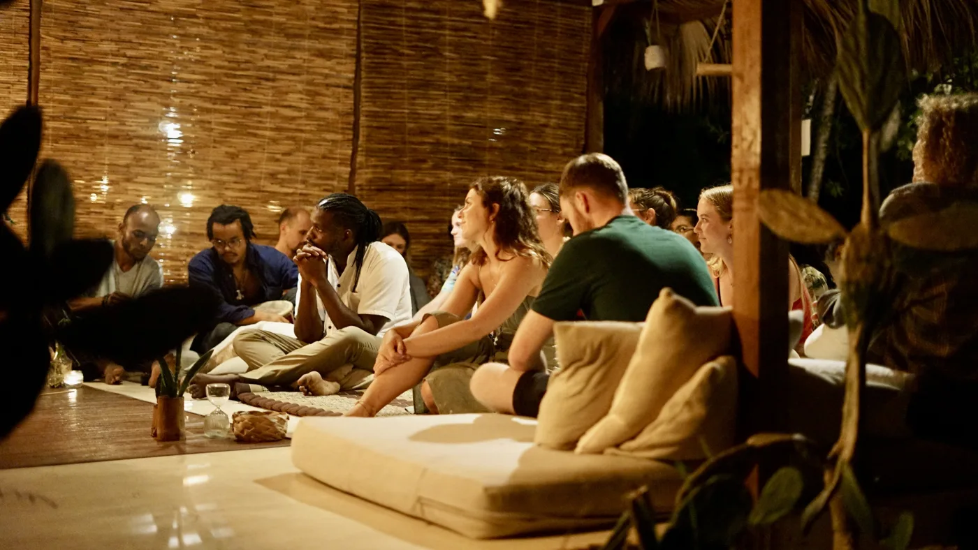 A group sitting in a circle in the shala in the evening